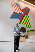 ArtLifting artist Rudolph Jean-Louis stands in front of his artwork at WS Development in Boston.